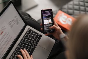 Image of a woman using a mobile phone to browse messages within an online social group.